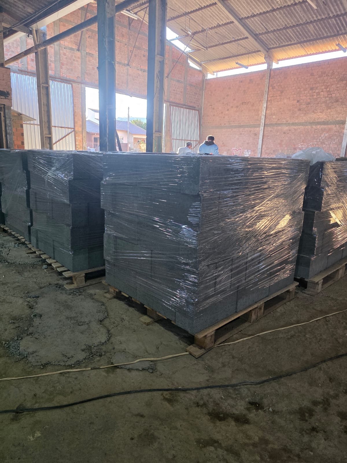 Pallets de blocos de concreto embalados com filme plástico no galpão da Grifo Artefatos